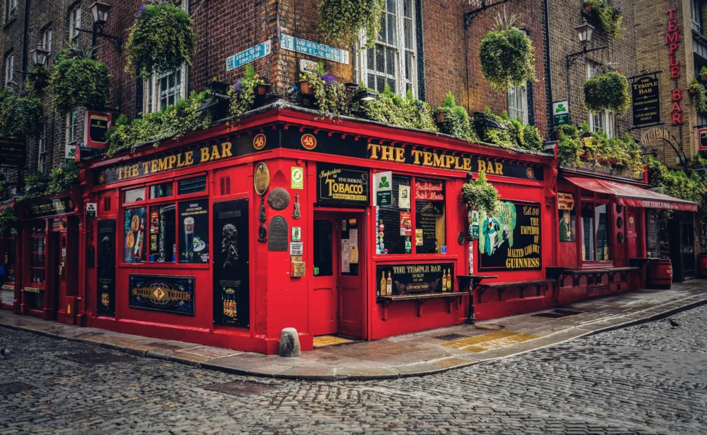 Things to do in Dublin - The Temple Bar (Image Source: Photo by <a href="https://unsplash.com/@lnlnln?utm_content=creditCopyText&utm_medium=referral&utm_source=unsplash">Leonhard Niederwimmer</a> on <a href="https://unsplash.com/photos/a-red-building-with-a-bunch-of-plants-on-top-of-it-yqWPwxhyYqs?utm_content=creditCopyText&utm_medium=referral&utm_source=unsplash">Unsplash</a>
  )